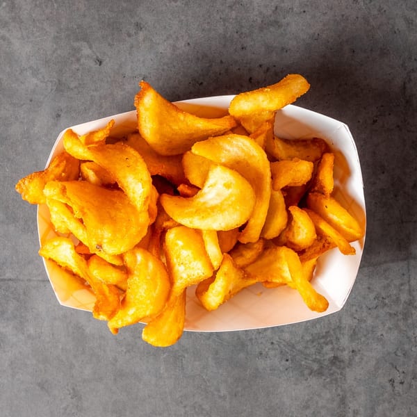 Golden curly fries in a white paper tray, viewed from directly above on a dark gray surface.