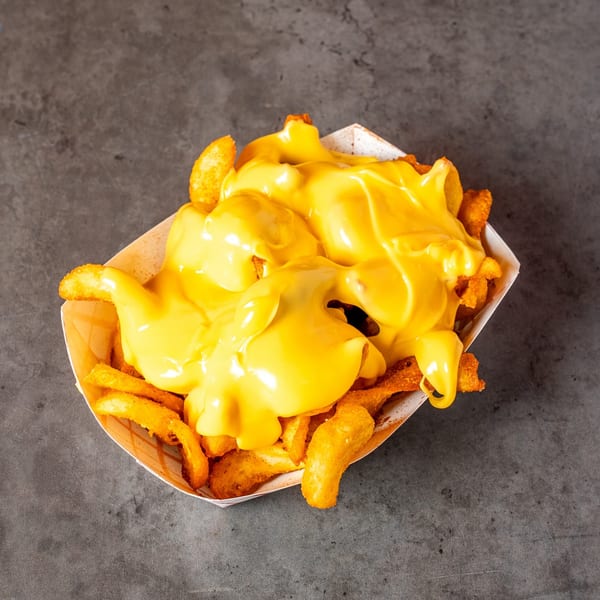 Golden french fries generously covered in melted yellow cheese sauce, served in a paper tray.