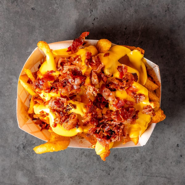 Overhead view of a basket of golden french fries smothered in melted cheese and crispy bacon bits.