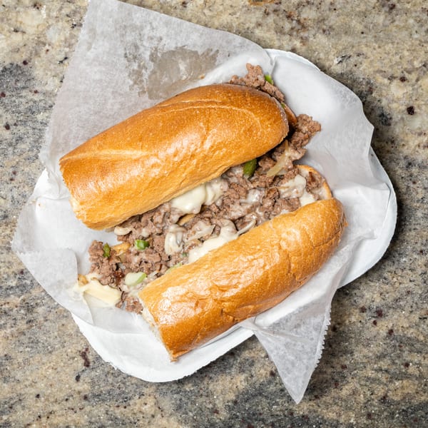 A delicious cheesesteak sandwich with melted cheese, meat, and peppers on a hoagie roll.